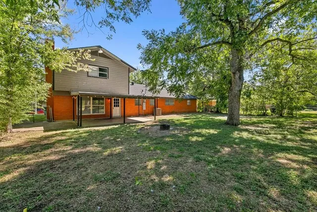 a view of a house with backyard and a tree