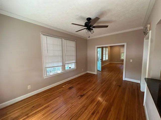 a view of empty room with wooden floor and fan
