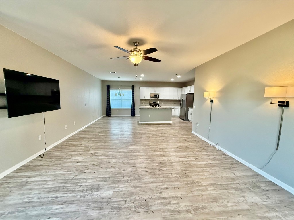 305 Rusk Bluff Avenue Leander, TX 78641 - Photo 14 of 34 a view of a livingroom with a flat screen tv wooden floor and a ceiling fan