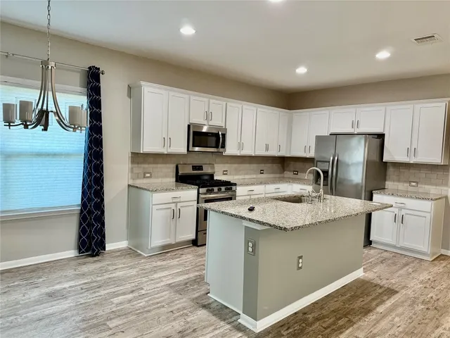 a kitchen with stainless steel appliances granite countertop a refrigerator sink and stove