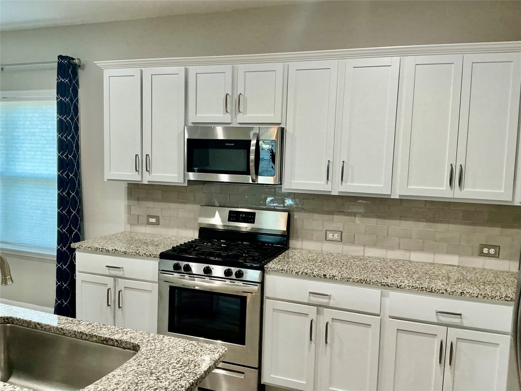 305 Rusk Bluff Avenue Leander, TX 78641 - Photo 9 of 34 a kitchen with granite countertop a sink stove and microwave
