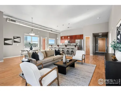 a living room with furniture kitchen view and a wooden floor