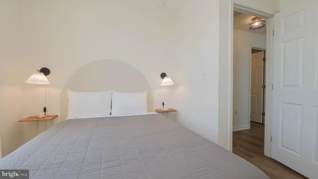 a view of a hallway with wooden floor and a bathroom
