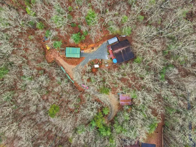 a backyard of a house with table and chairs under an umbrella