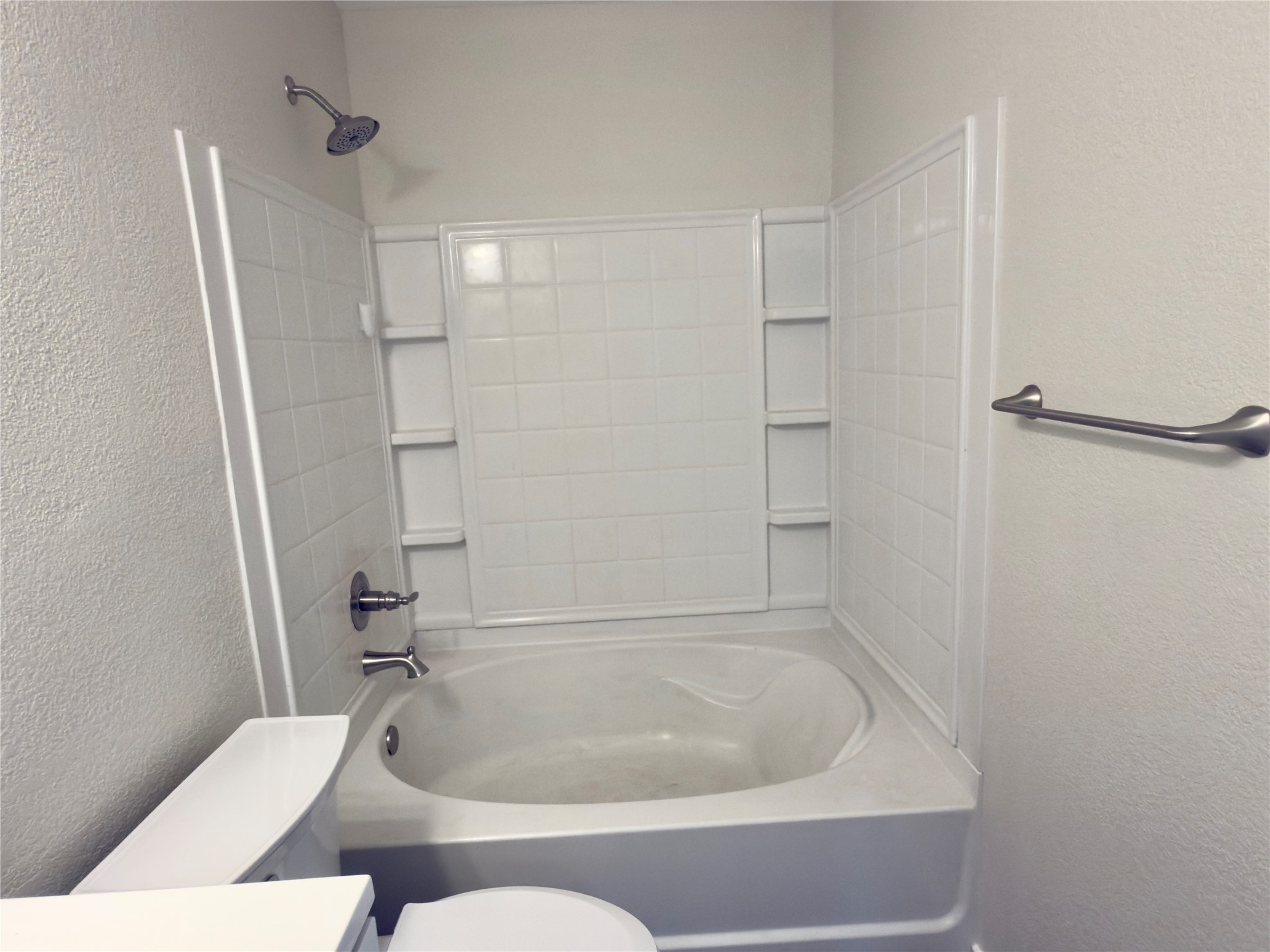 255 Myrtle Street Kyle, TX 78640 - Photo 20 of 31 White bathtub with integrated shower, chrome fixtures, and built-in shelving