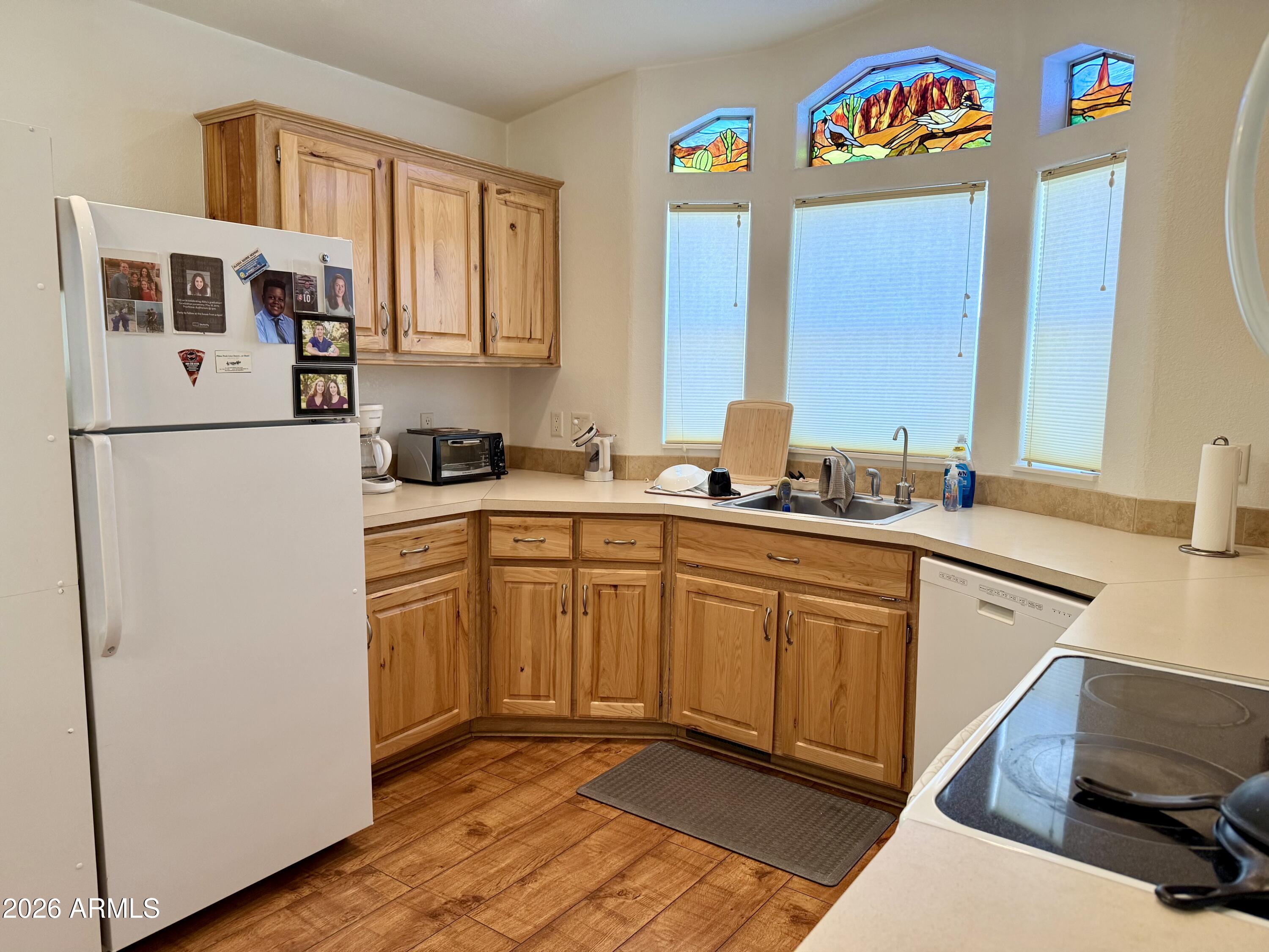 7750 East Broadway Road, Unit 197 Mesa, AZ 85208 - Photo 7 of 38 a kitchen with stainless steel appliances granite countertop a refrigerator a sink and a stove with wooden floor