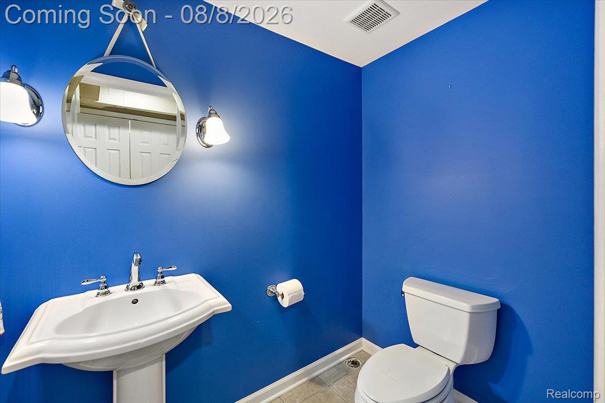 1150 West Eleven Mile Road Berkley, MI 48072 - Photo 10 of 29 Pedestal sink with chrome faucet, circular wall mirror, and wall-mounted sconces