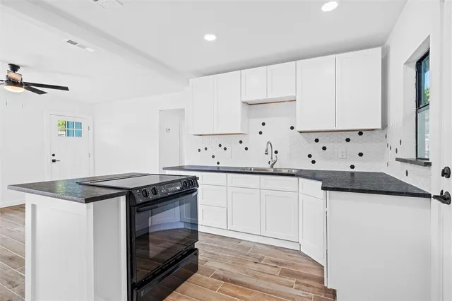 a kitchen with granite countertop white cabinets and a stove