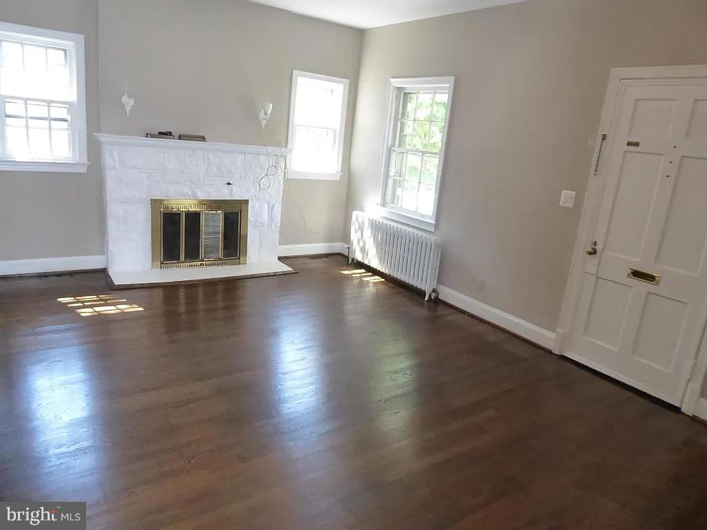 4344 Ellicott Street Northwest Washington, DC 20016 - Photo 2 of 25 an empty room with wooden floor a fireplace and windows