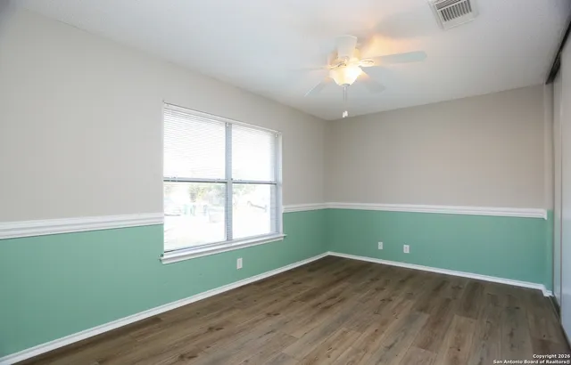 an empty room with wooden floor and windows