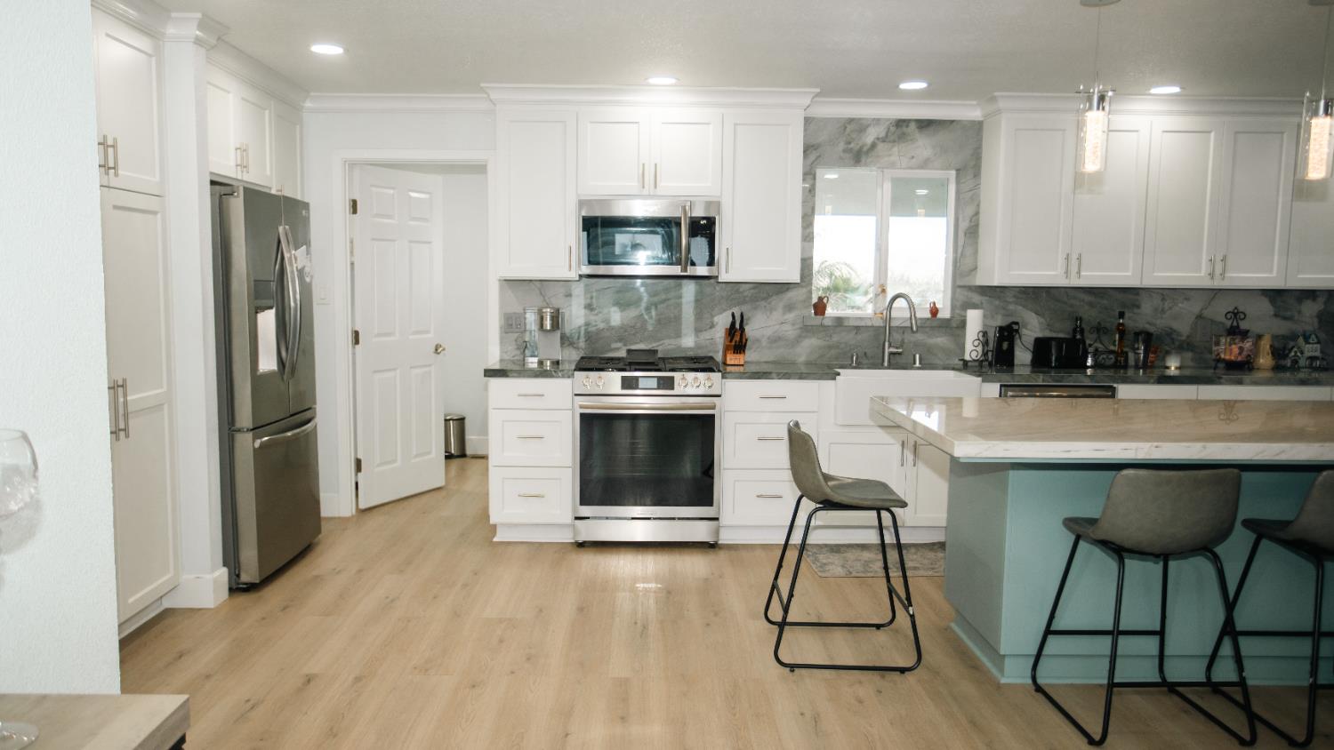 9115 East Southland Road Manteca, CA 95336 - Photo 3 of 52 a kitchen with stainless steel appliances a stove a sink refrigerator and a microwave