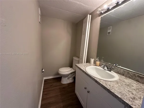 a bathroom with a granite countertop sink toilet and mirror