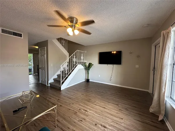 a view of a livingroom with wooden floor stairs and a flat screen tv