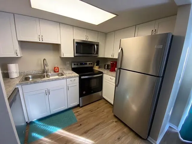 a kitchen with a refrigerator sink and cabinets
