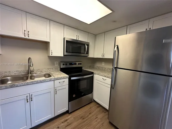 a kitchen with stainless steel appliances a refrigerator sink and microwave