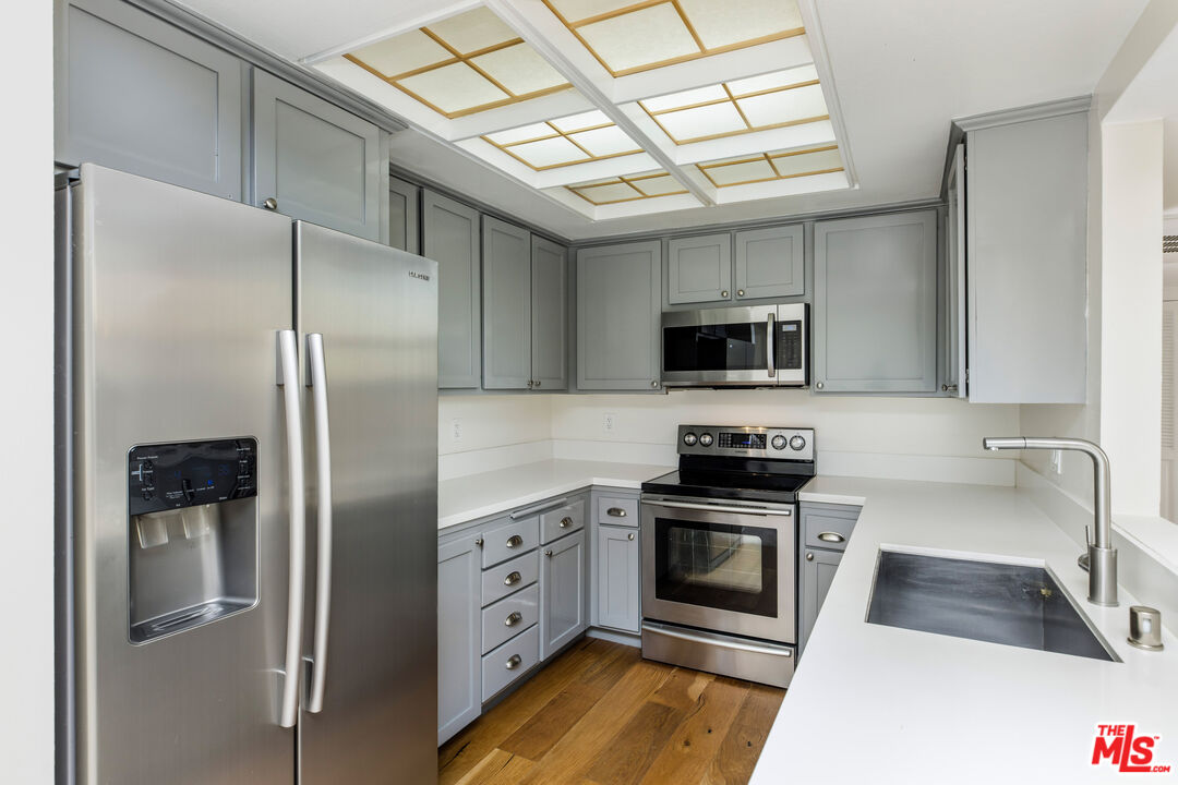 2385 Roscomare Road, Unit F4 Los Angeles, CA 90077 - Photo 17 of 57 a kitchen with stainless steel appliances granite countertop a refrigerator a stove and a sink with wooden floor