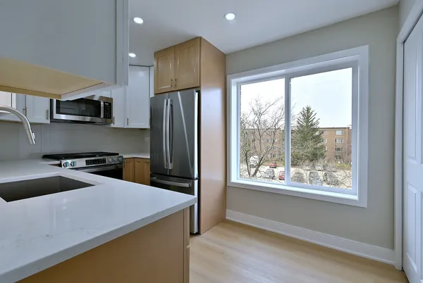 a kitchen with a refrigerator a stove a sink and a large window