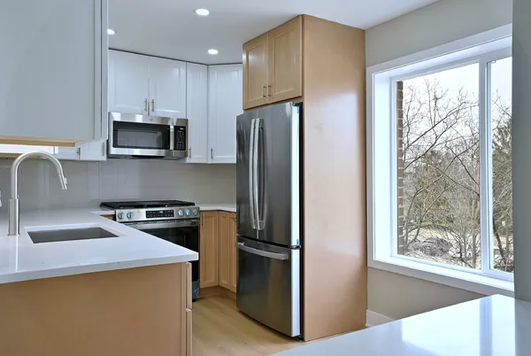 a kitchen with stainless steel appliances granite countertop a refrigerator a stove a sink and a window