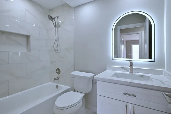 a bathroom with a toilet sink vanity tub and mirror