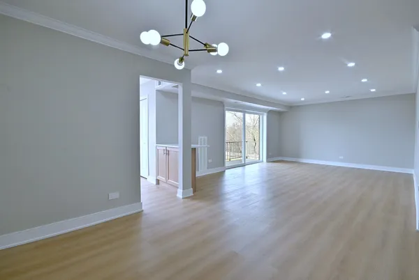 a view of an empty room with wooden floor and windows