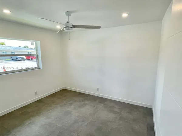 an empty room with windows and ceiling fan