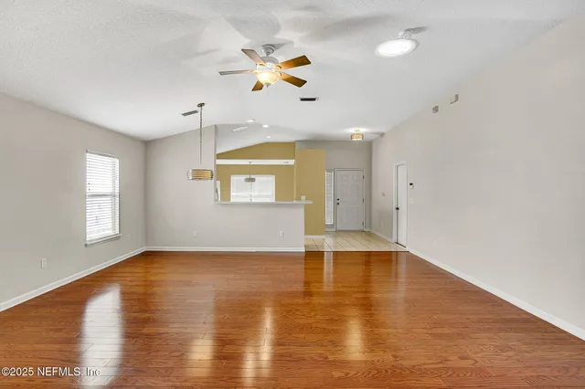 a view of an empty room with window and wooden floor