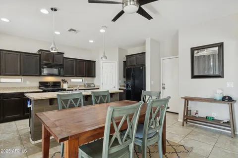 a kitchen with stainless steel appliances granite countertop a stove top oven a sink a dining table and chairs