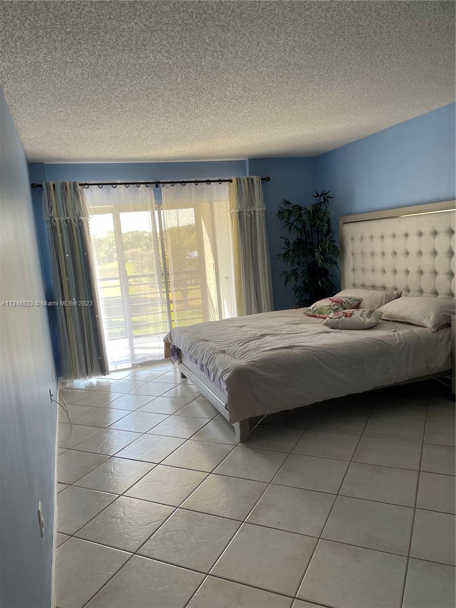 23370 Carolwood Lane, Unit 2202 Boca Raton, FL 33428 - Photo 8 of 31 a bedroom with a bed and a large window