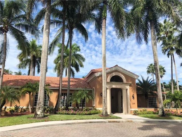 front view of house with a yard and palm trees