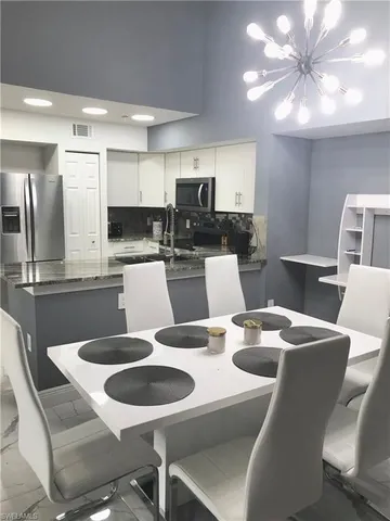 a kitchen with a dining table chairs and a refrigerator