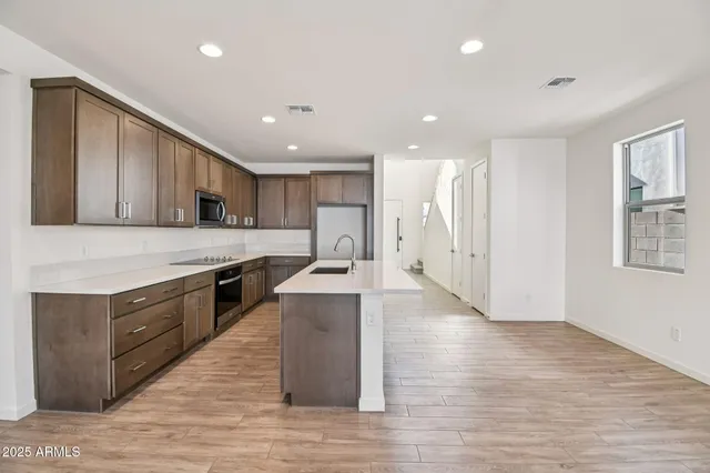 a large kitchen with stainless steel appliances granite countertop a large counter top and wooden floors