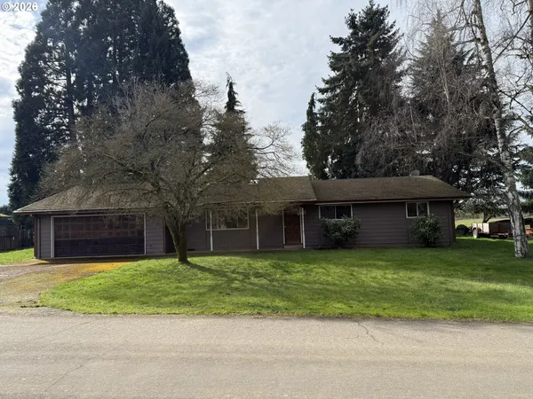 a view of a brick house with a yard and large trees