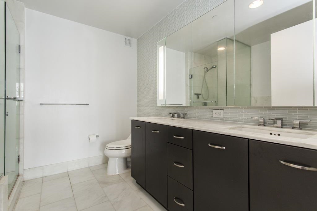 2 2nd Street, Unit 3304 Jersey City, NJ 07302 - Photo 12 of 25 a bathroom with a double vanity sink toilet and mirror