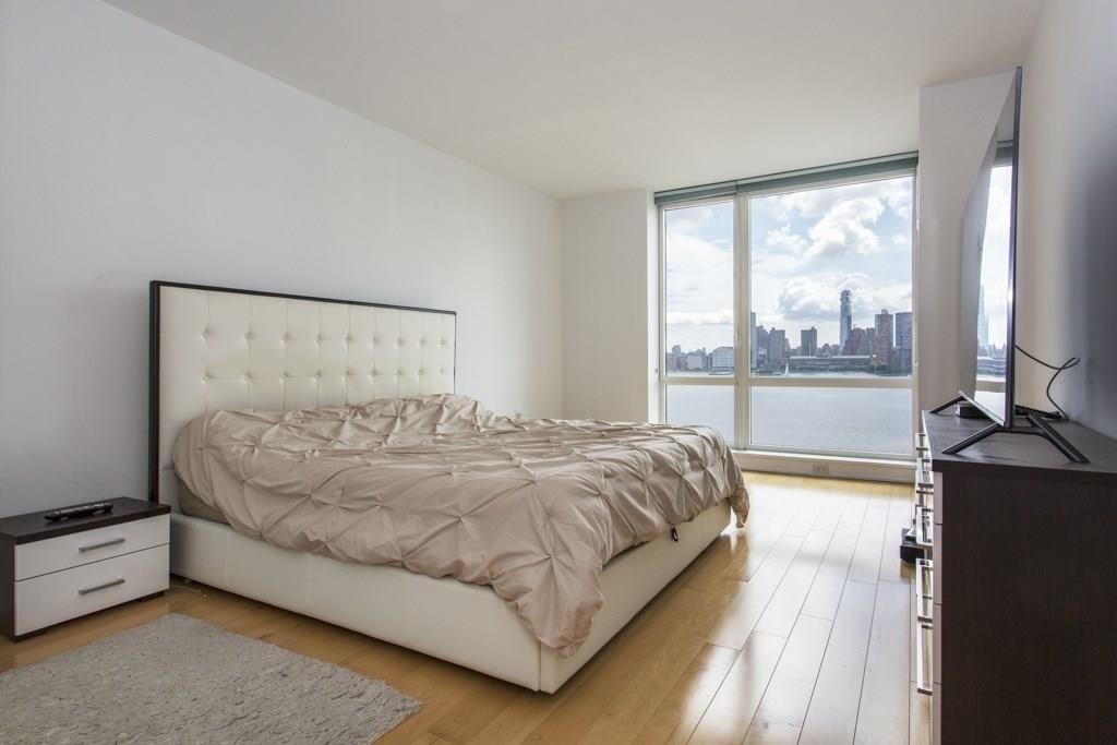 2 2nd Street, Unit 3304 Jersey City, NJ 07302 - Photo 9 of 25 a bed sitting in a bedroom next to a window