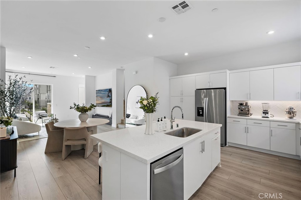 1826 West Bushell Street Anaheim, CA 92805 - Photo 14 of 30 a kitchen with sink a refrigerator and white cabinets with wooden floor