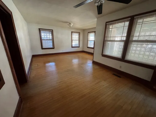 an empty room with wooden floor and windows