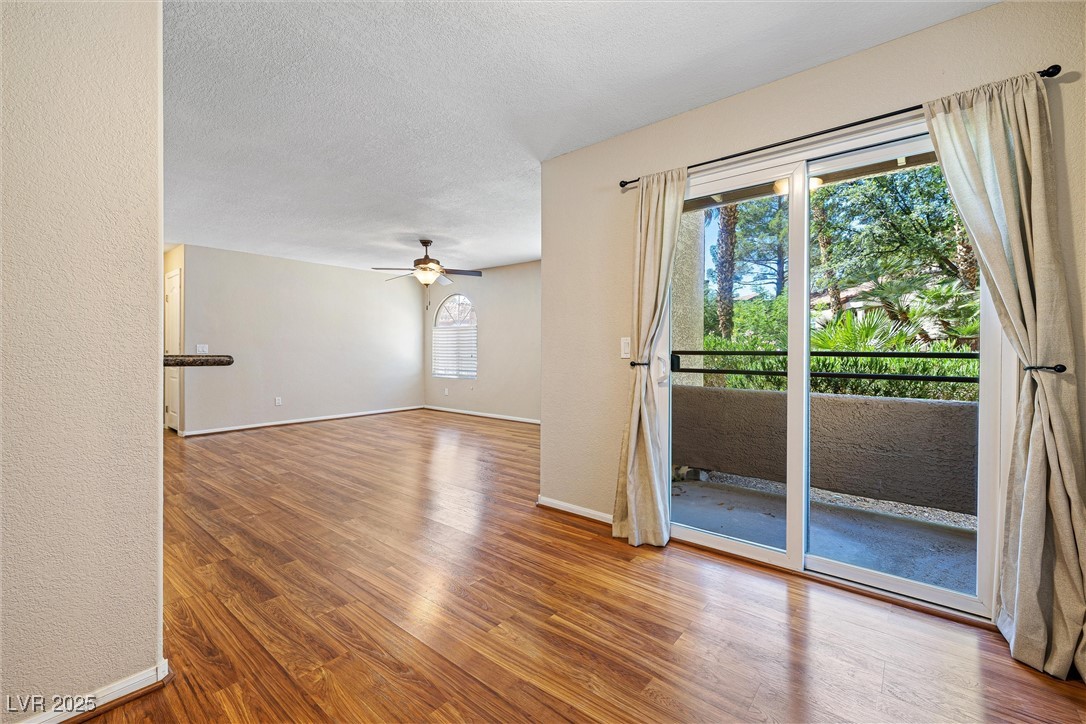 9325 West Desert Inn Road, Unit 104 Las Vegas, NV 89117 - Photo 8 of 25 Unfurnished room featuring wood finished floors, ceiling fan, and a textured ceiling