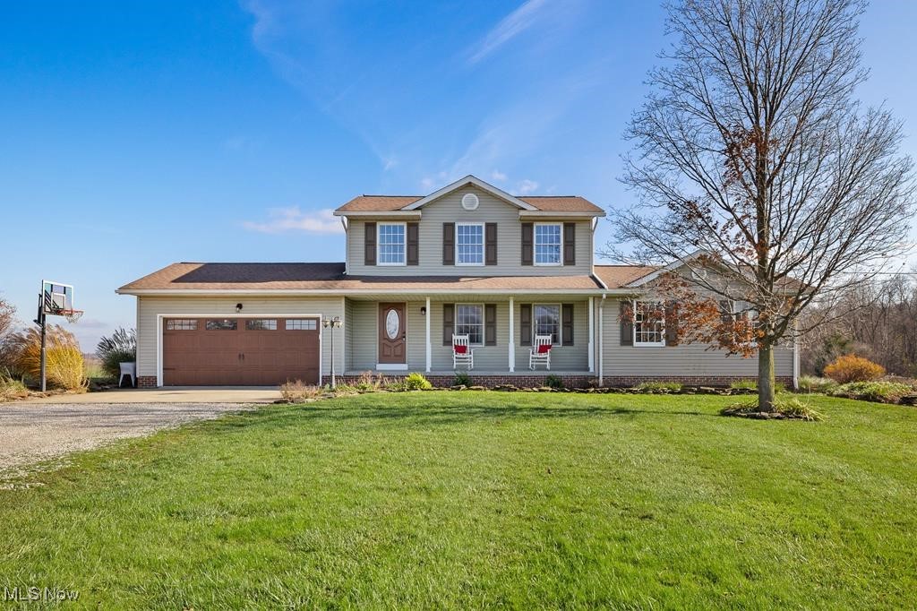 View of front of house featuring a front lawn, covered porch, and a garage