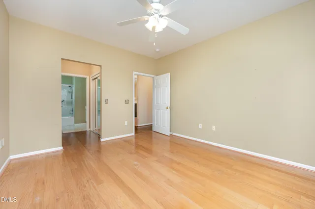 an empty room with wooden floor and a ceiling fan