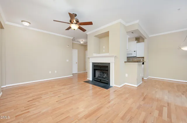 a view of empty room with wooden floor fireplace and ceiling fan
