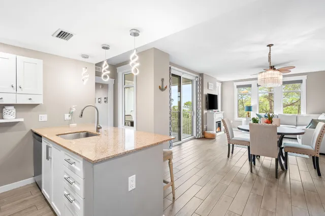 a open kitchen with stainless steel appliances granite countertop a stove top oven a sink dishwasher a dining table and chairs with wooden floor