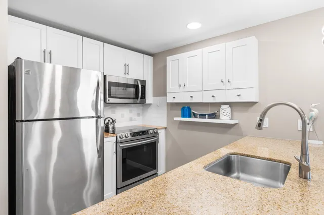 a kitchen with stainless steel appliances granite countertop a refrigerator sink and stove