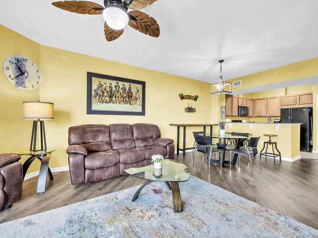 a living room with couches coffee table and kitchen view with wooden floor