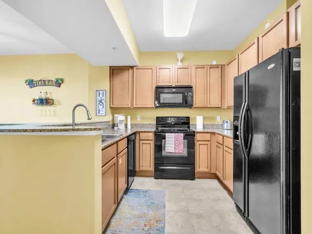 a kitchen with stainless steel appliances granite countertop a refrigerator a stove and a sink with wooden cabinets