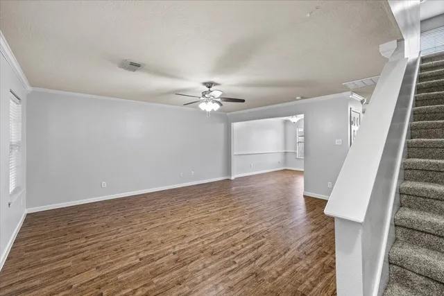 a view of an empty room with wooden floor and staircase