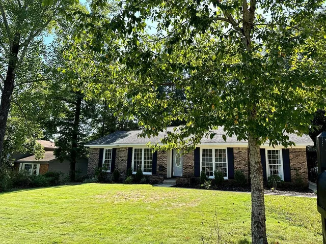 a front view of a house with yard and tree