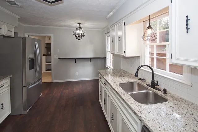 a kitchen with stainless steel appliances granite countertop a sink dishwasher a refrigerator and cabinets with wooden floor