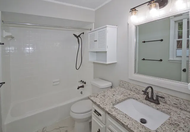 a bathroom with a granite countertop sink toilet and shower