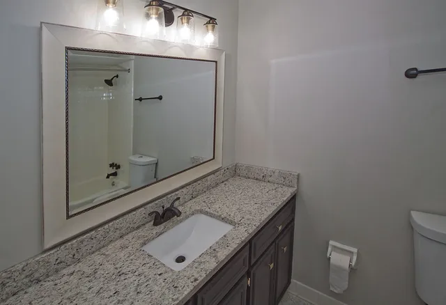 a bathroom with a granite countertop sink a toilet and shower