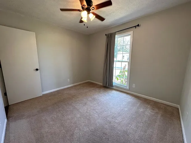 an empty room with a window and a fan